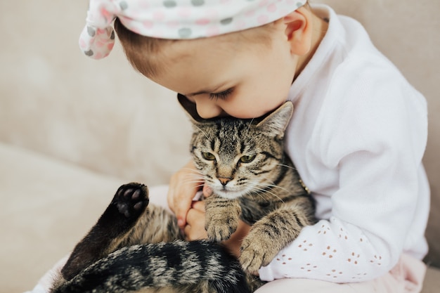 niña abrazando y besando a su gato rayado