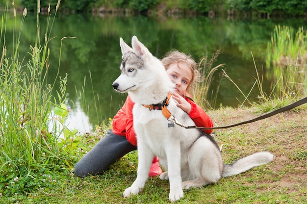 Niña abrazando husky siberiano en la naturaleza