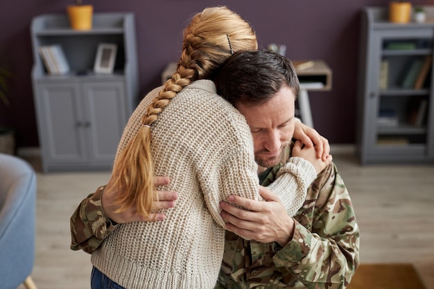 Niña abrazando a papá militar en casa en un momento de unión