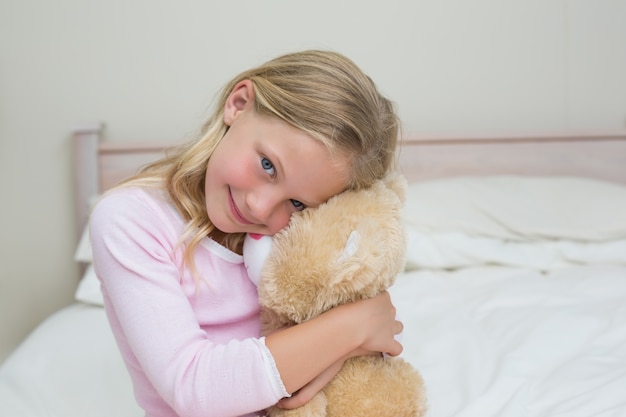 Niña abrazando peluche en la cama