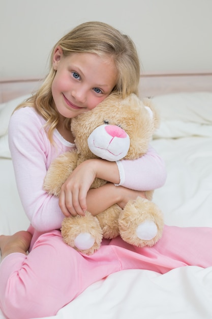 Niña abrazando peluche en la cama