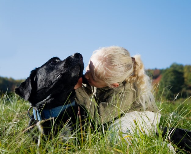 niña abrazando perro negro