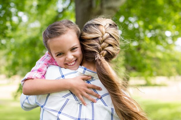 Niña abrazando a su madre en el parque