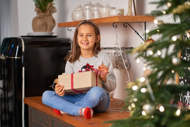 Foto niña abre una caja con un regalo de navidad de santa
