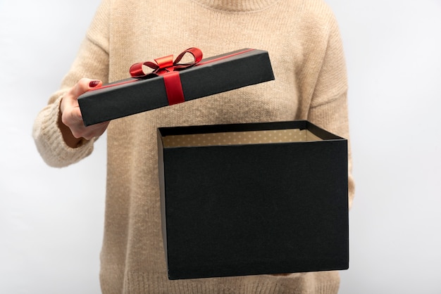 Niña abre caja de regalo negra con lazo rojo. Celebracion.