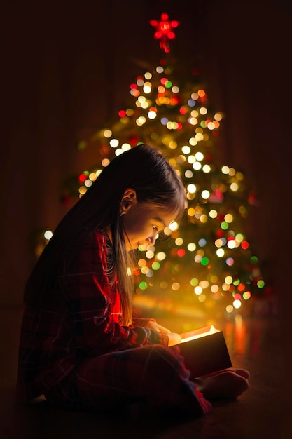 Foto una niña abre un regalo de papá noel en la noche de navidad un tiempo de magia y milagros