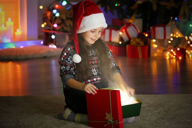 Niña abriendo regalo de Navidad en la sala de estar