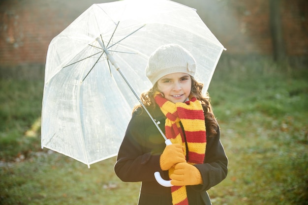Niña con un azul con un paraguas blanco en el parque en otoño. alta calidad | Foto Premium