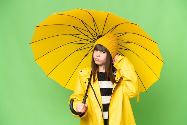 Niña con abrigo impermeable y paraguas sobre un fondo aislado de clave de croma que tiene dudas