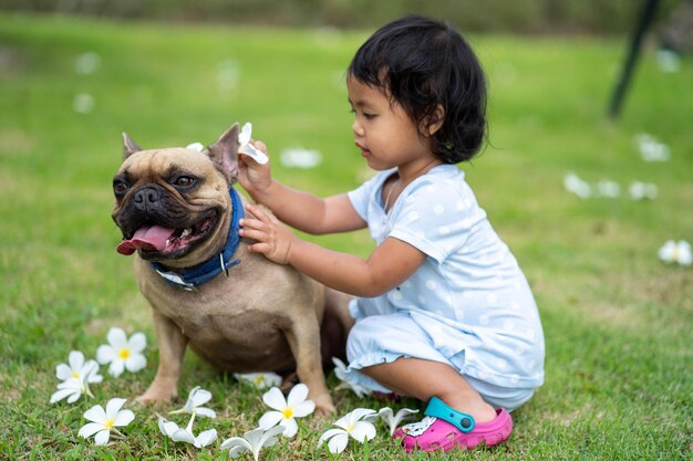 Una niña acariciando a un perro en un césped