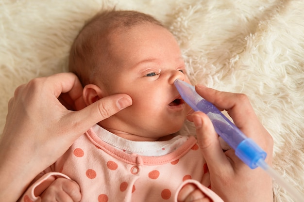 Niña acostada en la cama y madre con gotas nasales, niño con la boca abierta mirando hacia otro lado, niño viste durmiente con puntos, bebé en una manta mullida.