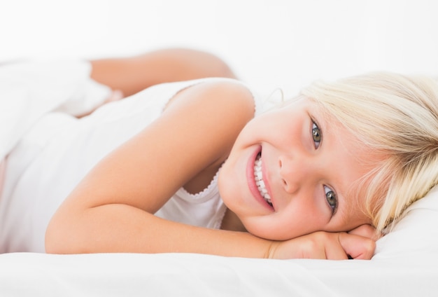 Niña acostada en una cama y sonriendo