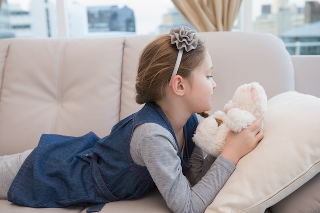 Niña acostada en el sofá con teddy