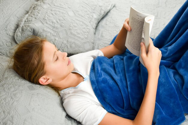 niña se acuesta en la cama con un libro