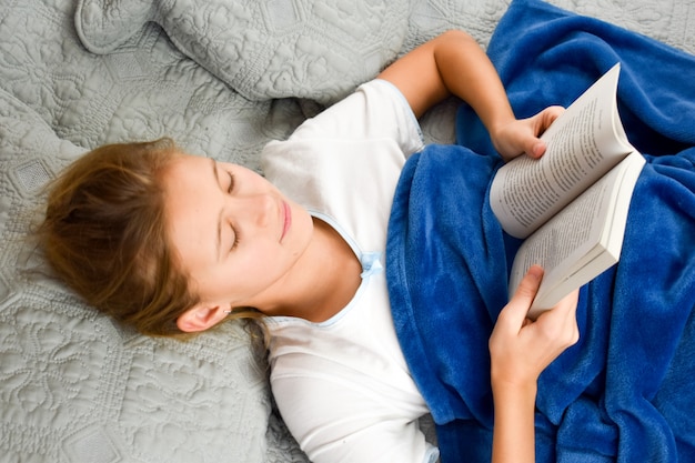 niña se acuesta en la cama con un libro