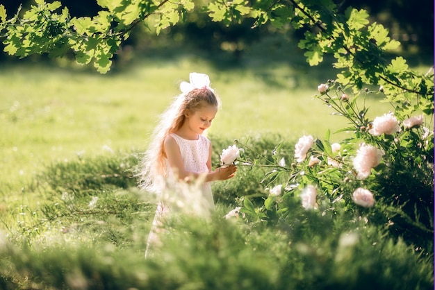 Niña admira las flores. Un niño se ocupa de las peonías.