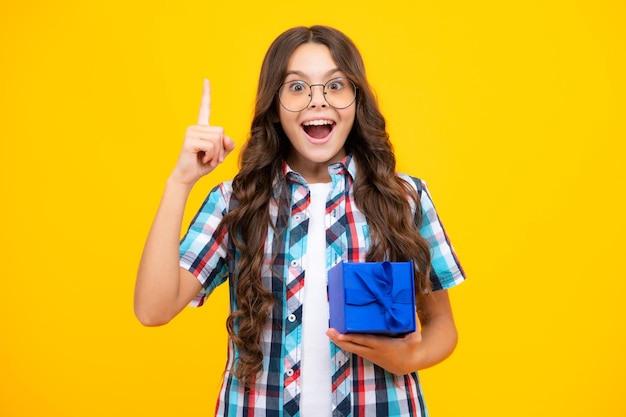 Niña adolescente asombrada Niño niña adolescente 1214 años con regalo sobre fondo amarillo aislado Concepto actual de vacaciones de cumpleaños Expresión emocionada alegre y alegre