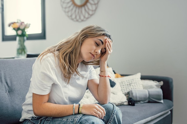 Niña adolescente deprimida o cansada que siente estrés dolor de cabeza dolor sentada sola en casa molesta triste de corazón roto joven que se arrepiente del embarazo o el aborto preocupada por un problema o trauma psicológico