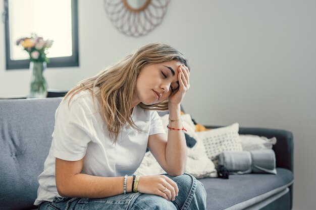 Niña adolescente deprimida o cansada que siente estrés dolor de cabeza dolor sentada sola en casa molesta triste de corazón roto joven que se arrepiente del embarazo o el aborto preocupada por un problema o trauma psicológico