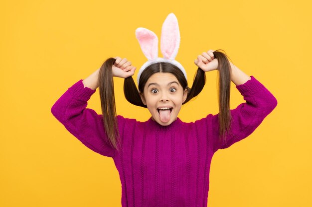 niña adolescente divertida y juguetona en orejas de conejo sosteniendo su cabello, vacaciones de pascua.