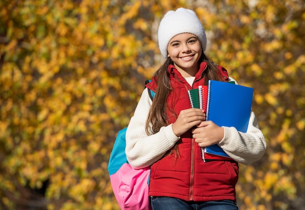 Niña adolescente feliz de regreso a la escuela en el espacio de copia de otoño