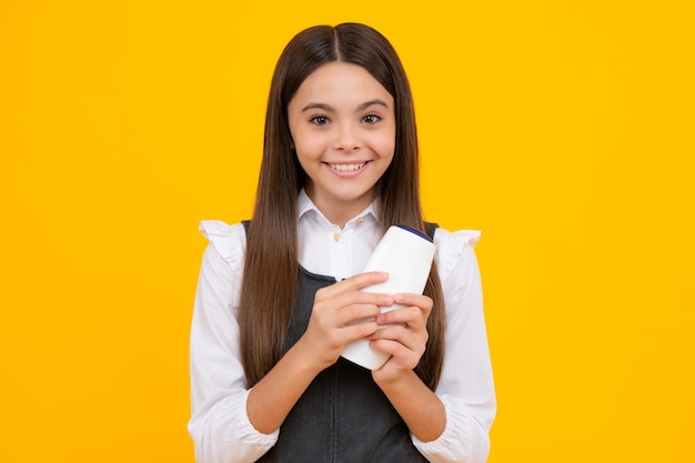 Niña adolescente mostrando acondicionadores de champú o gel de ducha botella de producto cosmético para el cabello