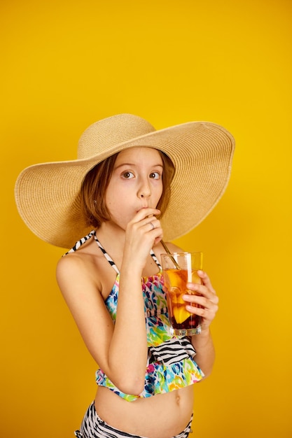 Niña adolescente niño en traje de baño y sombrero de paja con limonada