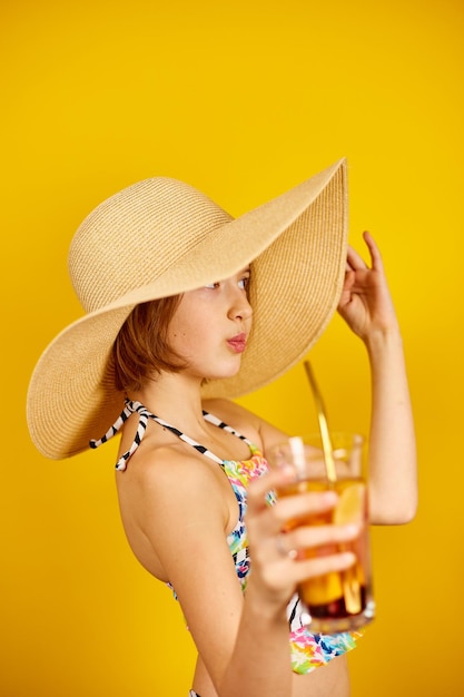 Niña adolescente niño en traje de baño y sombrero de paja con limonada