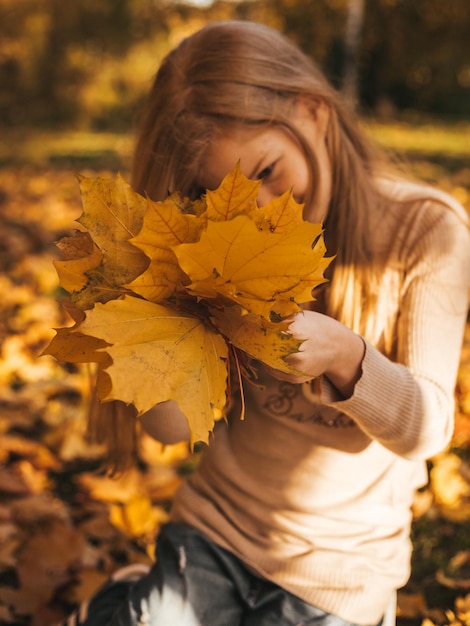 Niña adolescente con pecas en un paseo entre hojas amarillas en colores de otoño otoño