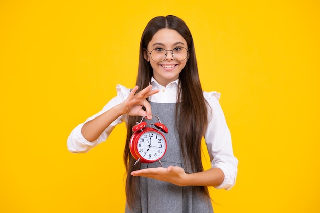 Niña adolescente puntual comprobando el tiempo Niño con reloj despertador que muestra la hora Cara feliz emociones positivas y sonrientes de niña adolescente