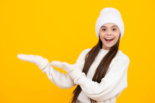 Niña adolescente señalando hacia un lado con un dedo para presentar un producto o idea Niña adolescente en ropa informal señalando un espacio vacío