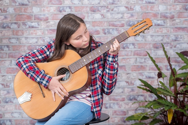 Niña adolescente sonriente tocando la guitarra acústica