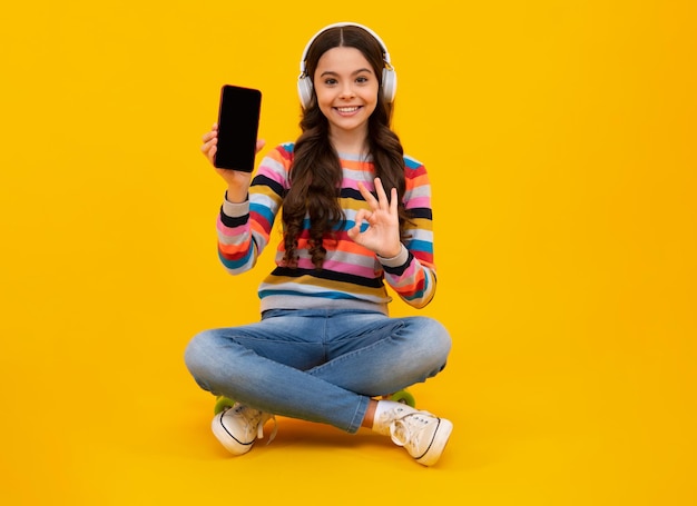Niña adolescente sosteniendo un teléfono inteligente Niña hipster con teléfono celular Niño sosteniendo un teléfono móvil enviando mensajes de texto en las redes sociales en línea Niño mostrando una pantalla en blanco de un teléfono móvil simulado espacio de copia