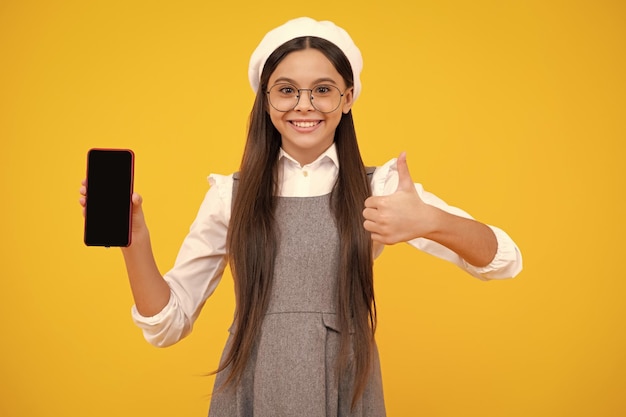 Niña adolescente con teléfono inteligente Niña hipster con teléfono móvil Niño con teléfono móvil enviando mensajes de texto en redes sociales en línea Niño mostrando pantalla en blanco teléfono móvil