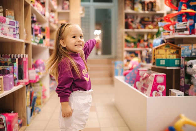 Una niña adorable comprando juguetes una mujer linda en una tienda de juguetes una niña joven feliz seleccionando juguetes