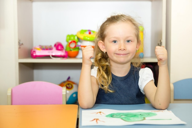 Niña adorable dibuja un pincel y pinta en la sala de guardería