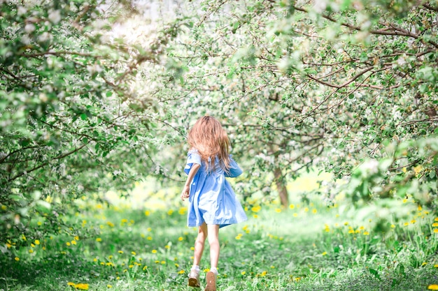 Niña adorable en jardín floreciente de apple en el hermoso día de primavera