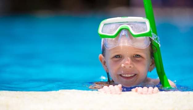 Niña adorable en la máscara y gafas en piscina