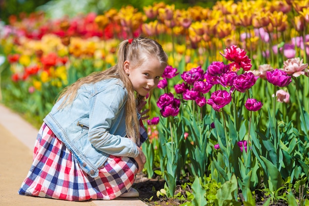 Niña adorable que huele coloridos tulipanes en día de verano