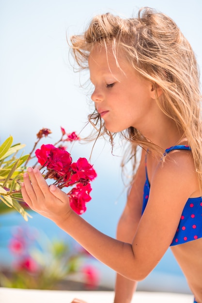 Niña adorable que huele flores coloridas en el día de verano