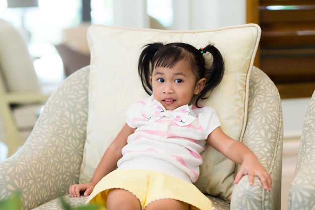 Una niña adorable sentada en el sofá.