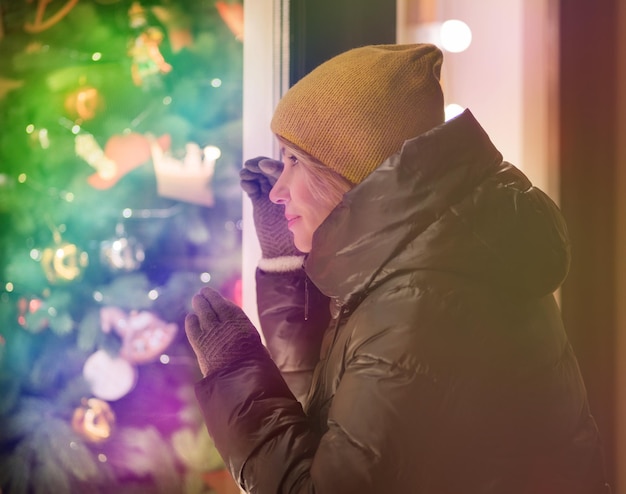 Una niña adulta en un estado de cuento de hadas de Navidad mira un escaparate festivo Estado de ánimo festivo Enfoque suave