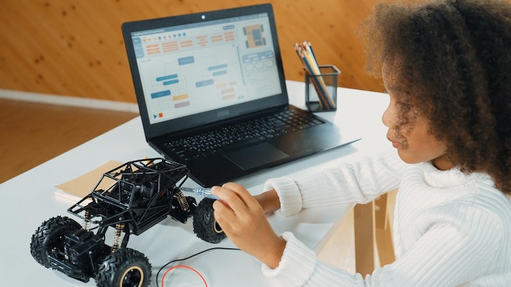 Foto niña africana construye un coche robótico mientras usa cables mientras usa una erudición portátil