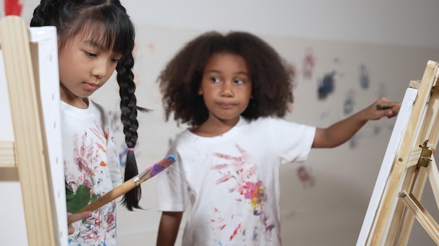Niña africana creativa pintó o dibujó lienzo junto con un niño asiático Erudición