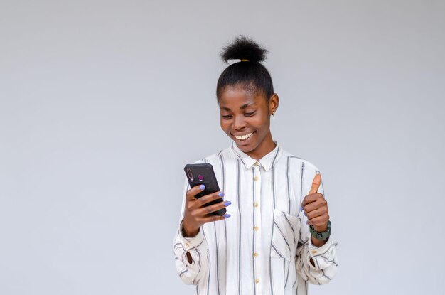 Niña africana, tenencia, teléfono, sonriente, con, ella, pulgares arriba