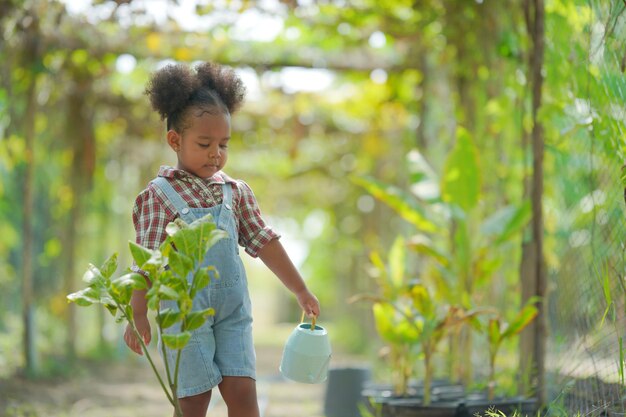 Niña afro que tiene actividades al aire libre en el jardín orgánico de la granja niño de familia diversa Concepto del día de la madre