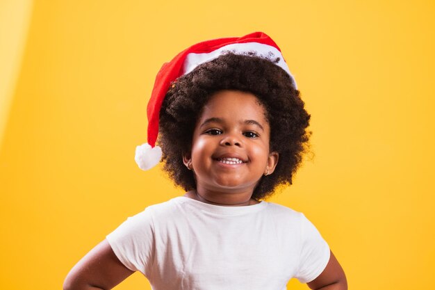 Niña afro con sombrero de Santa Claus sonriendo a la cámara