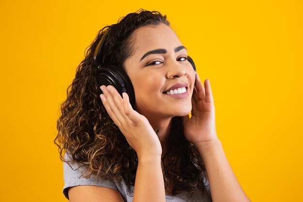 Niña afro con sus auriculares escuchando música. De cerca