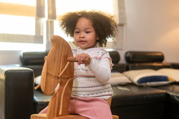 Niña afroamericana feliz jugando en la sala de estar en casa