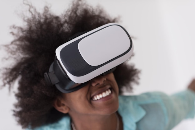 Niña afroamericana feliz obteniendo experiencia usando gafas de realidad virtual VR, aislada en fondo blanco